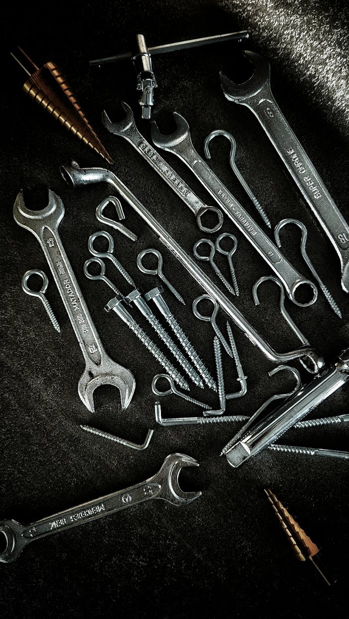gallery-3 A collection of vintage metal tools, including wrenches and screws, laid out on a dark surface.