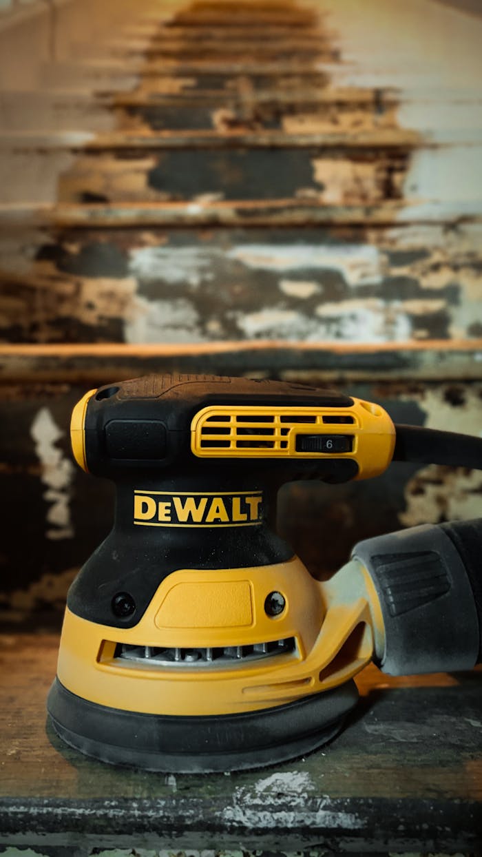 services-02 A DeWalt electric sander is prominently displayed on a worn staircase with peeling paint.