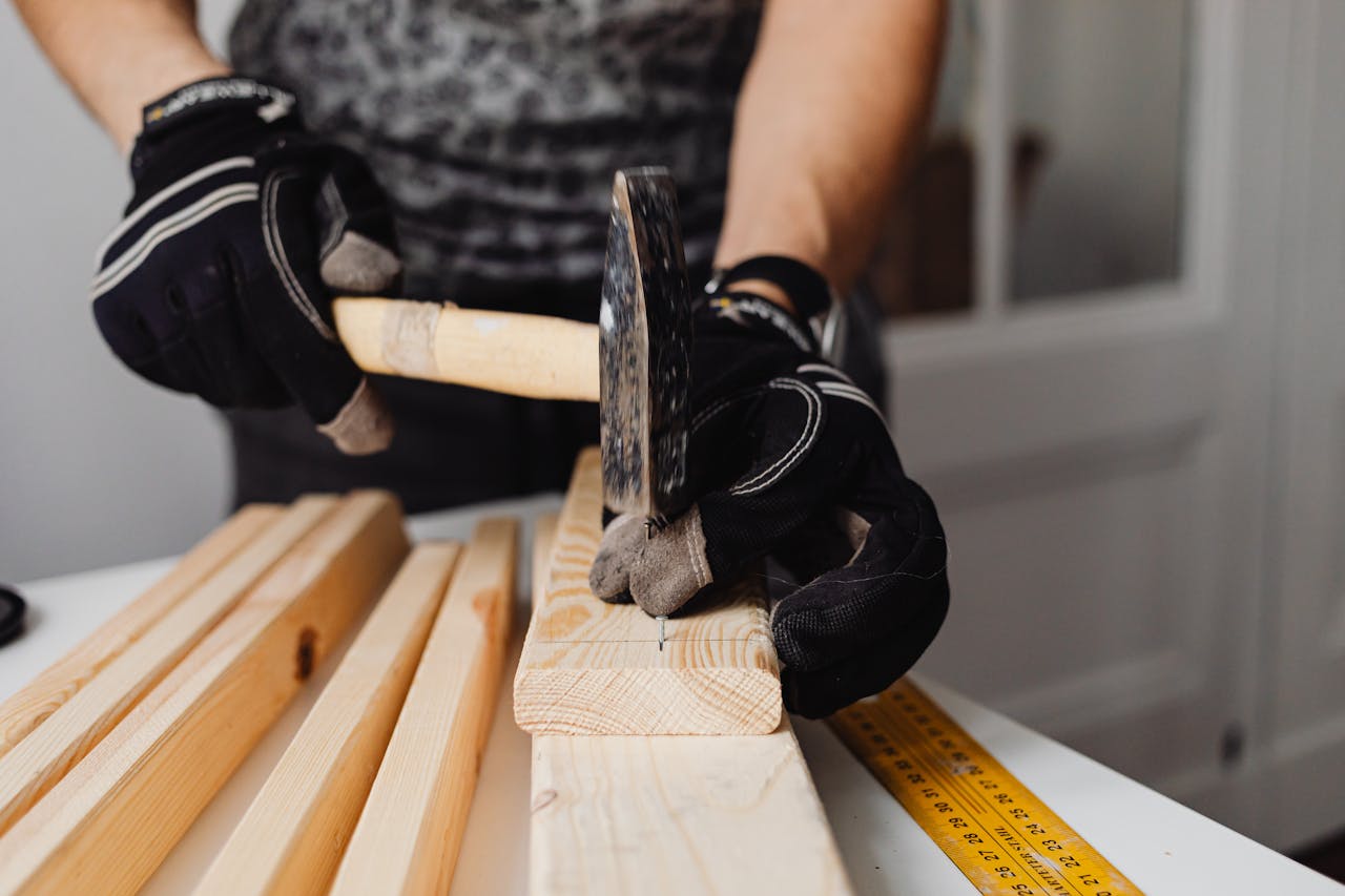 gallery-5 Craftsman hammering nails into wood, showcasing woodworking skills and tools in action.