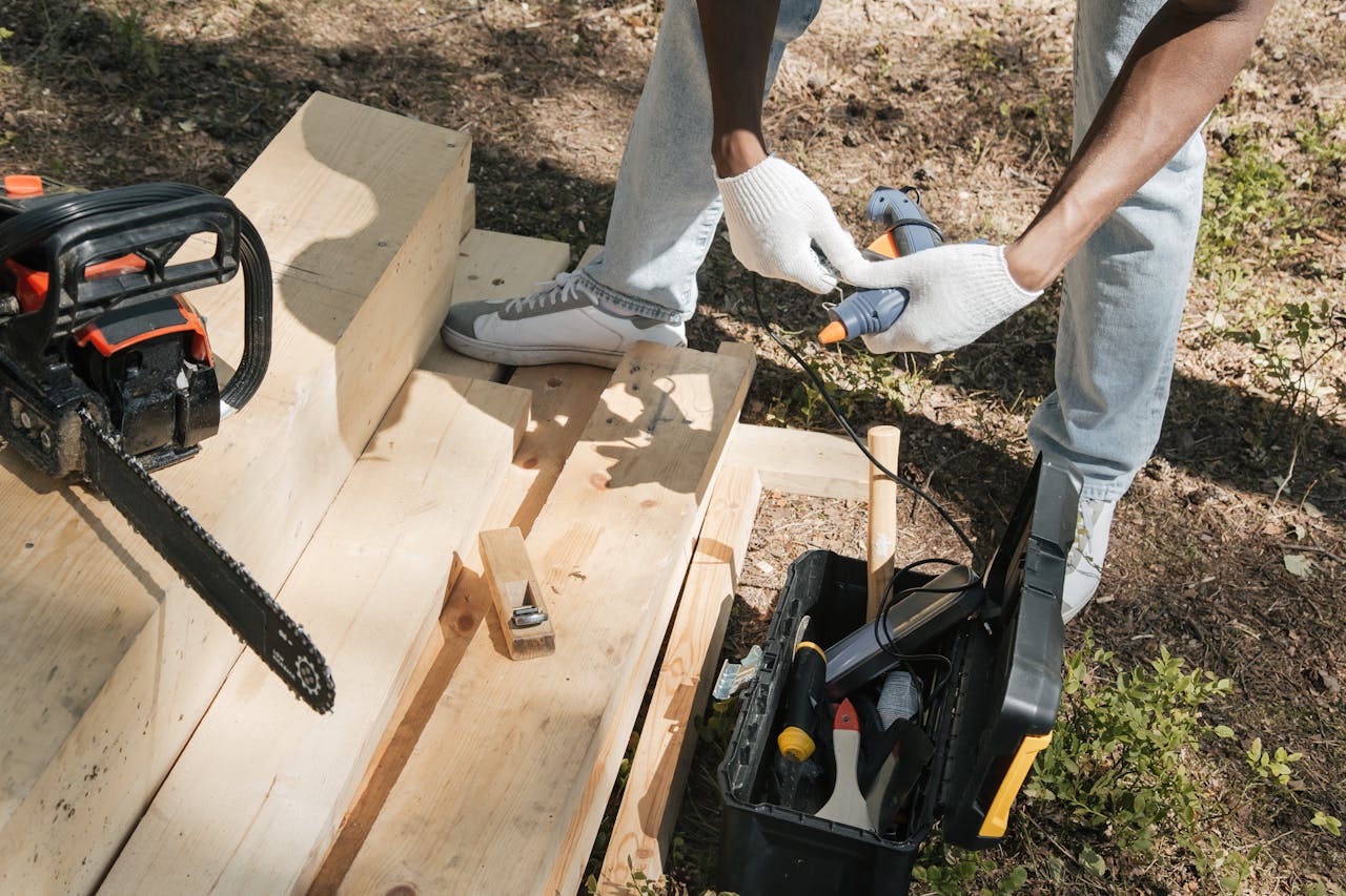 services-03 A carpenter using power tools to work on a wooden panel outdoors, showcasing construction and craftsmanship.